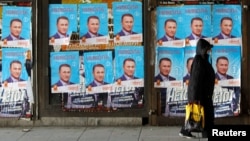 People walk next to posters of the candidates for the early parliamentary elections in Skopje, Macedonia, Dec. 8, 2016. 