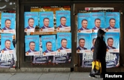 FILE - People walk next to posters of the candidates for the early parliamentary elections in Skopje, Macedonia, Dec. 8, 2016.