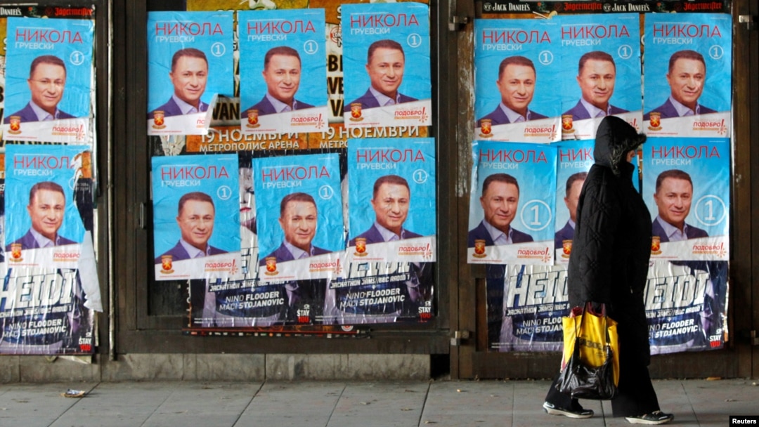 People walk next to posters of the candidates for the early parliamentary elections in Skopje, Macedonia, Dec. 8, 2016. 