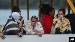 People who survived a sunken ferry, cry as they wait for more information about their missing friends and relatives, at a reservoir in Guatape, Colombia, June 25, 2017.