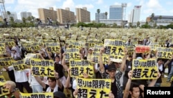 Protesters raise placards reading "Anger was over the limit" during a rally against the U.S. military presence on the island and a series of crimes and other incidents involving U.S. soldiers and base workers, at a park in capital Naha on Japan's southern island of Okinawa, Japan, in this photo taken by Kyodo June 19, 2016. 