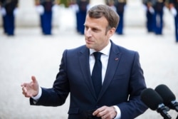 FILE - French President Emmanuel Macron talks with reporters in Paris, April 29, 2021. He said outdoor terraces of France's cafes and restaurants would be allowed to reopen on May 19, along with museums and some other venues under certain conditions.