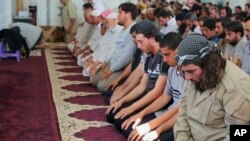 In this photo from the Islamic State-affiliated Rased News Network, Muslim worshippers attend Friday prayers in Qaryatain, Syria, Aug. 7, 2015; a banner in the mosque read, "Friday prayers after the conquest of Qaryatain," which occurred Aug. 6.