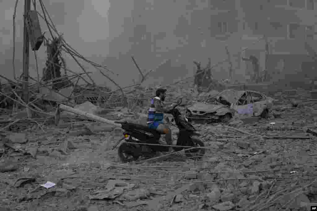 A man rides his scooter as he drives on the debris of destroyed buildings that were hit by Israeli airstrikes in Dahiyeh, Beirut, Lebanon.