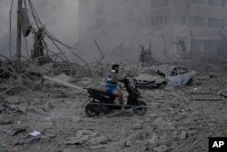 A man rides his scooter as he drives on the debris of destroyed buildings that were hit by Israeli airstrikes in Dahiyeh, Beirut, Lebanon, Oct. 6, 2024.