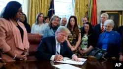 Tổng thống Donald Trump ký ban hành luật mới nhắm mục đích ngăn chặn nạn buôn người khai thác tình dục, ngày 11 tháng 4, 2018, trong Phòng Bầu dục tại Nhà Trắng ở Washington.
