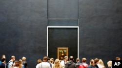 Visitors watch the Leonardo da Vinci's painting Mona Lisa, in Paris, Monday, July 6, 2020. The home of the world's most famous portrait, the Louvre Museum in Paris, reopened Monday after a four-month coronavirus lockdown. (AP Photo/ Thibault Camus)