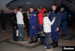 Russian cosmonaut Alexei Ovchinin, center, and U.S. astronaut Nick Hague, right front, meet with family members and acquaintances upon their arrival at Baikonur airport, Kazakhstan, Oct. 11, 2018.