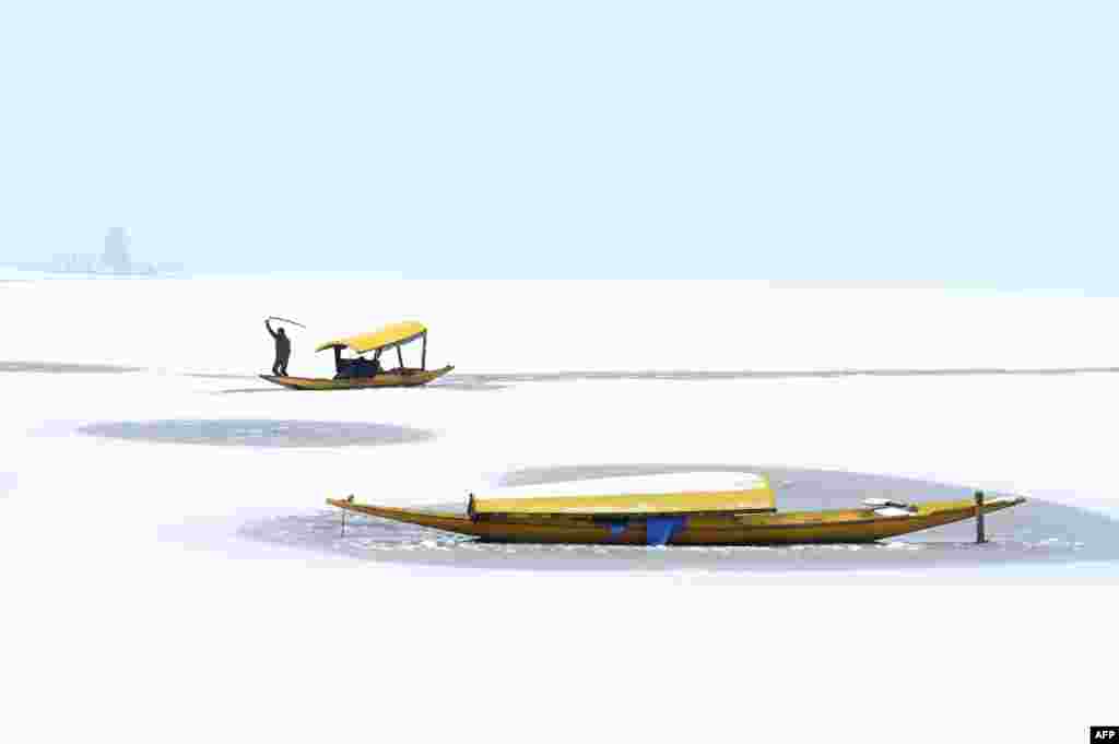 A boatman steers his boat at the partially frozen Dal Lake after a snowfall in Srinagar, India.