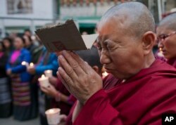 FILE - An exile Tibetan nun cries as she prays during a candlelit vigil in solidarity with two Tibetans, who exiles claim have immolated themselves demanding freedom for Tibet, in Dharmsala, India, Wednesday, March 2, 2016.