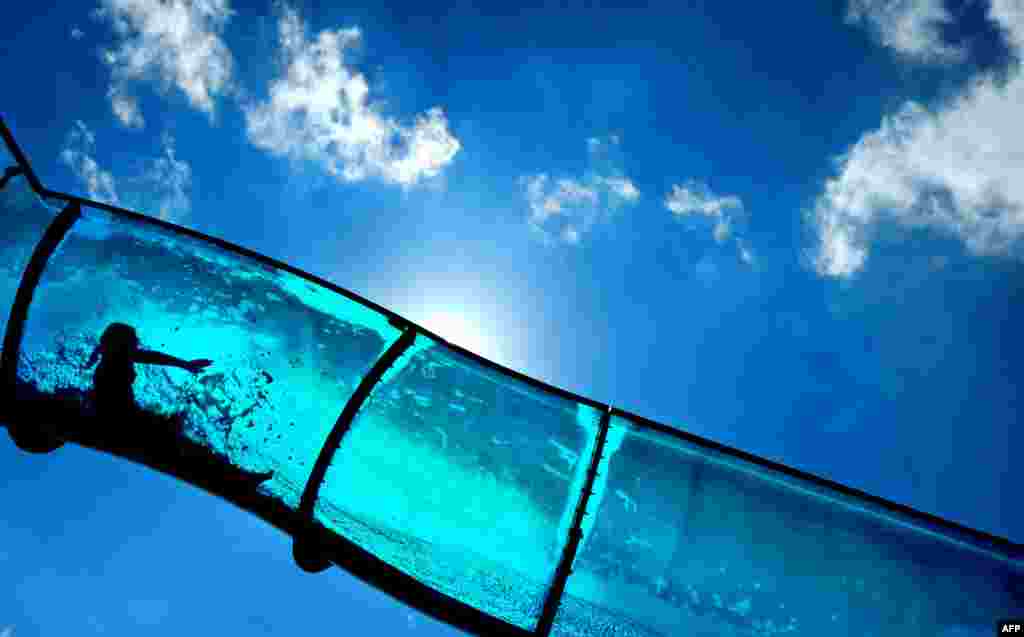 The silhouette of a child is visible in a water slide at an open air swimming pool in Mainz, Germany.