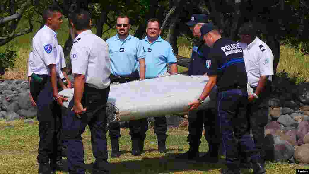 Des gendarmes et policiers français portent un morceau d&#39;avion trouvé sur la plage de Saint-André, 29 juillet 2015.