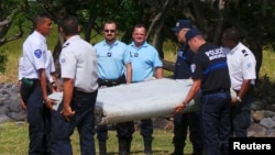 Cảnh sát Pháp khiêng mảnh vỡ lớn được tìm thấy trên bãi biển ở Saint-Andre, đảo Reunion của Pháp ở Ấn Độ Dương, 29/7/2015.