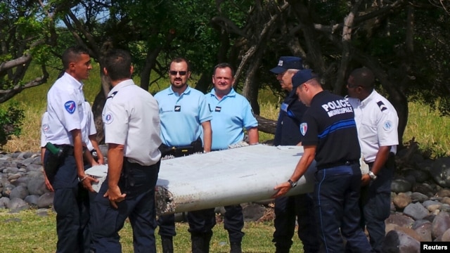 Gendarmes y policías franceses llevan una enorme pieza de un avión encontrada en la playa en Saint-Andre, la isla francesa de Reunión, en el Océano Índico.