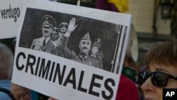 A protester holds a banner with a photo of Spanish dictator Gen. Francisco Franco with Adolf Hitler during a protest in Madrid, Spain, Thursday, Sept. 13, 2018. Relatives of victims of Spain's 20th century dictatorship gathered near the Spanish parliament as lawmakers debate and likely pass a bill to exhume late dictator Gen. Francisco Franco from a controversial mausoleum. 