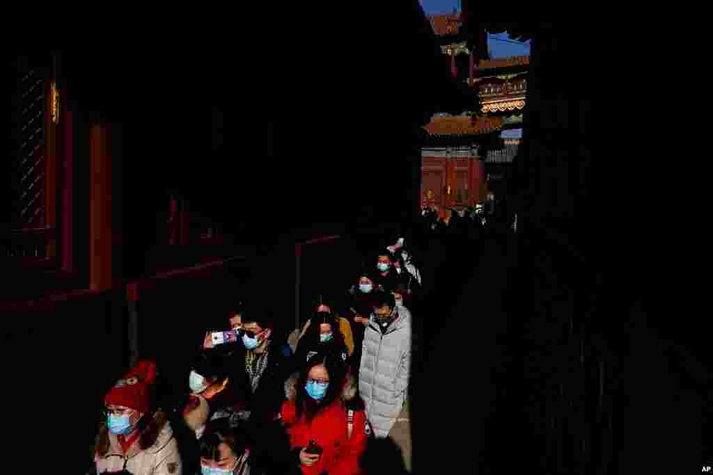 People wearing face masks to help curb the spread of the coronavirus visit Yonghegong Lama Temple as they offer prayers on the first day of the New Year in Beijing.