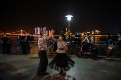 一对戴着口罩的夫妇在湖北省武汉市长江公园旁跳舞。（2020年5月12日）