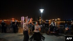 12일 중국 우한의 양쯔강변에서 마스크를 쓴 남녀가 춤을 추고 있다.