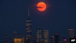 The full moon rises above the New York City skyline on the 50th anniversary of the Apollo 11 moon launch, Tuesday, July 16, 2019. (AP Photo/J. David Ake)