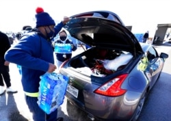 Water is loaded into the trunk of a car at a City of Houston water distribution site, Feb. 19, 2021, in Houston.