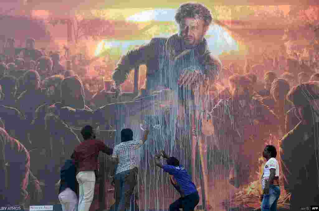 Indian fans spray milk on a billboard displaying the picture of Bollywood star Rajinikanth in a celebratory gesture intended to bless their favorite film star&#39;s new movie, before attending the show of the new Tamil-language film &#39;Pettai&#39; in Chennai, Jan. 10, 2019.