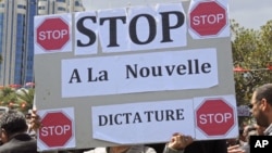 A supporter of the former regime holds banner during a rally to protest the upcoming elections in Tunis. Banner reads,"Stop to the new dictatorship", (File)