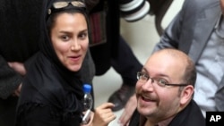 FILE - Jason Rezaian (R), an Iranian-American correspondent for The Washington Post, and his wife Yeganeh Salehi, an Iranian correspondent for the Abu Dhabi-based newspaper The National, attend a presidential campaign of President Hassan Rouhani in Tehran, Apr. 11, 2013.
