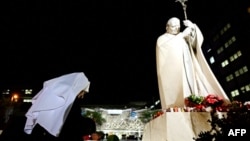 A nun prays in front of a statue of Pope John Paul II outside the Gemelli hospital where Pope Francis is hospitalized for tests and treatment for respiratory infection, in Rome, Feb. 18, 2025. 