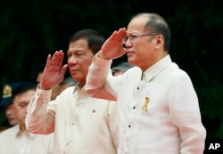 New Philippine President Rodrigo Duterte, left, and outgoing President Benigno Aquino III salute during inauguration ceremony Thursday, June 30, 2016.