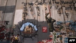 Uma criança brinca em frente a um graffiti que representa a reconstrução de Gaza, numa secção da barreira de separação de Israel, em Belém, na Cisjordânia ocupada, a 12 de fevereiro de 2025.