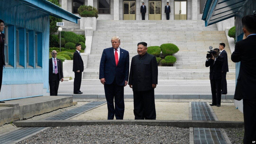 Presiden AS Donald Trump dan pemimpin Korea Utara Kim Jong Un berdiri di wilayah Korea Utara di zona demiliterisasi (DMZ), hari Minggu (30/6). 