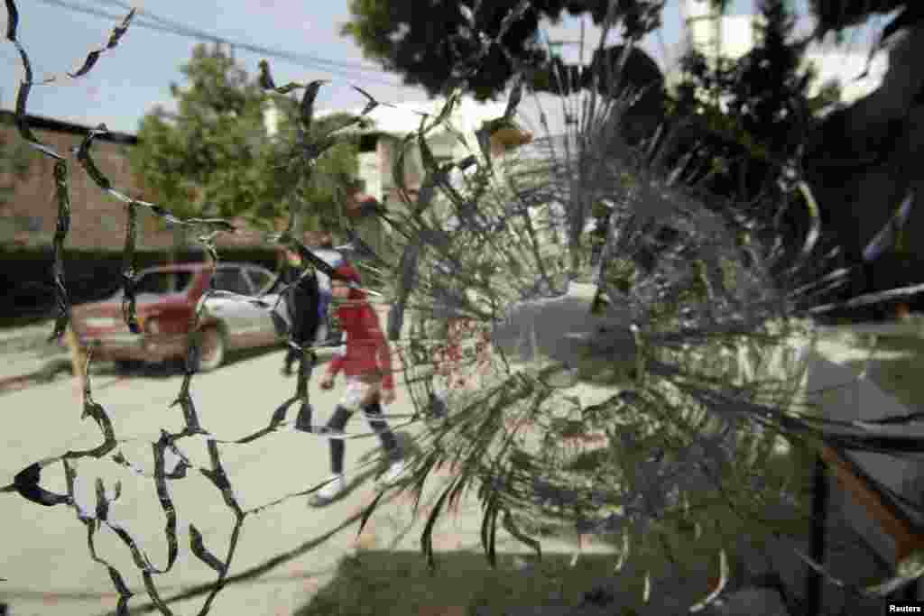 A girl is pictured through a broken window after clashes at Ain al-Hilweh Palestinian refugee camp near the port city of Sidon in south Lebanon. Ten people were wounded and one killed during clashes between the Fatah movement and radical Islamists that started on March 11, 2013.