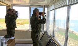 FILE - Russian Defense Minister Sergei Shoigu, center, and General Staff Valery Gerasimov watch drills in Crimea, in this handout photo taken from a video released April 22, 2021, by Russian Defense Ministry Press Service.