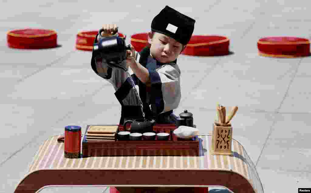 A child wearing a costume performs a tea ceremony ahead of the Dragon Boat Festival in Shenyang, Liaoning province. The festival is commemorated in memory of Chinese patriotic poet Qu Yuan, who drowned himself in 277 B.C.