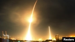 FILE - A long exposure photograph shows the SpaceX Falcon 9 lifting off (L) from its launch pad and then returning to a landing zone (R) at the Cape Canaveral Air Force Station.