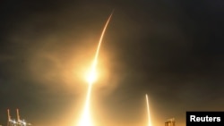 FILE - A long-exposure photograph shows the SpaceX Falcon 9 lifting off (L) from its launch pad and then returning to a landing zone (R) at the Cape Canaveral Air Force Station, in Cape Canaveral, Florida, Dec. 21, 2015.