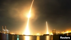 A long exposure photograph shows the SpaceX Falcon 9 lifting off (L) from its launch pad and then returning to a landing zone (R) at the Cape Canaveral Air Force Station, on the launcher's first mission since a June failure, in Cape Canaveral, Florida, De