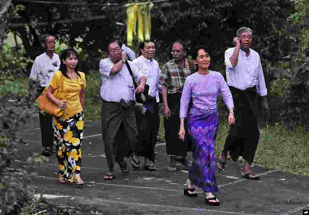 Burma's opposition leader Aung San Suu Kyi (2R) walks towards the gate of her house to meet with supporters after her release in Rangoon, 13 Nov 2010.