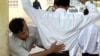 FILE - A Cambodian school security official searches a student for exam 'cheat sheets' at the gates of a school in Phnom Penh.