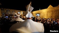Para penari berputar menampilkan tarian tradisional Sufi selama bulan suci Ramadan di depan Masjid Umayyah, Damaskus, Suriah, 8 Juni 2018. (REUTERS / Omar Sanadiki)