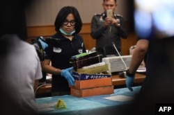 FILE - An employee from the Department of Special Investigation sorts through evidence from a massage parlor after police raided the premises because of suspicions of underage trafficking and prostitution, in Bangkok, Jan. 15, 2018.