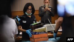 FILE - An employee from the Department of Special Investigation sorts through evidence from a massage parlor after police raided the premises because of suspicions of underage trafficking and prostitution, in Bangkok, Jan. 15, 2018.