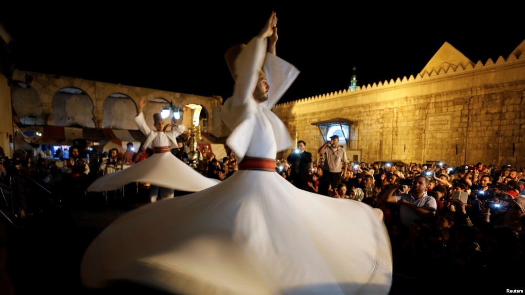 Para penari berputar menampilkan tarian tradisional Sufi selama bulan suci Ramadan di depan Masjid Umayyah, Damaskus, Suriah, 8 Juni 2018. (REUTERS / Omar Sanadiki)