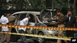 Indian police forensics experts investigate the scene after an explosion tore through a car belonging to the Israel Embassy in New Delhi, India, February 13, 2012.
