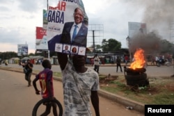 A demonstrator holds up a poster of Kenya's opposition leader and presidential candidate Raila Odinga, as protests erupt after the presidential election results were announced, declaring Deputy President William Ruto the winner, in Kisumu, Kenya August 15, 2022. (REUTERS/Baz Ratner)