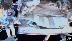 FILE - This NASA photo shows the view from astronaut Andrew Morgan's helmet cam as Italian colleague Luca Parmitano works outside the International Space Station during a spacewalk, Jan. 25, 2020.