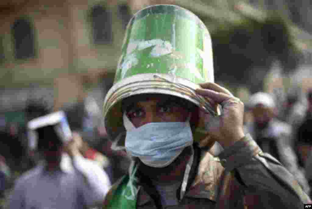 An Egyptian anti-government protester uses a bucket as a helmet during clashes in Cairo's Tahrir square, Egypt, Thursday, Feb. 3, 2011. Protesters and regime supporters skirmished in a second day of rock-throwing battles at a central Cairo square while ne