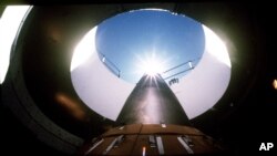 An LGM-118A Peacekeeper intercontinental ballistic missile points skyward from its position in a silo