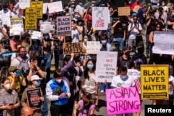 FILE - Demonstrators hold signs during a rally against hate crimes outside City Hall in Los Angeles, March 27, 2021.