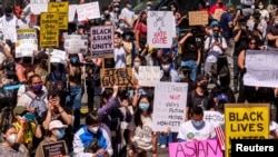 Demonstrators hold signs during a rally against anti-Asian hate crimes outside City Hall in Los Angeles, March 27, 2021. 